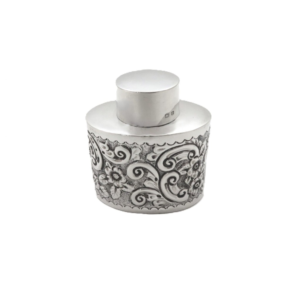 An antique late Victorian sterling silver tea caddy featuring repousse floral scroll decoration and a smooth fitted cap lid. View VII