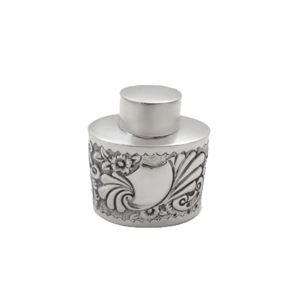 An antique late Victorian sterling silver tea caddy featuring repousse floral scroll decoration and a smooth fitted cap lid. View IX