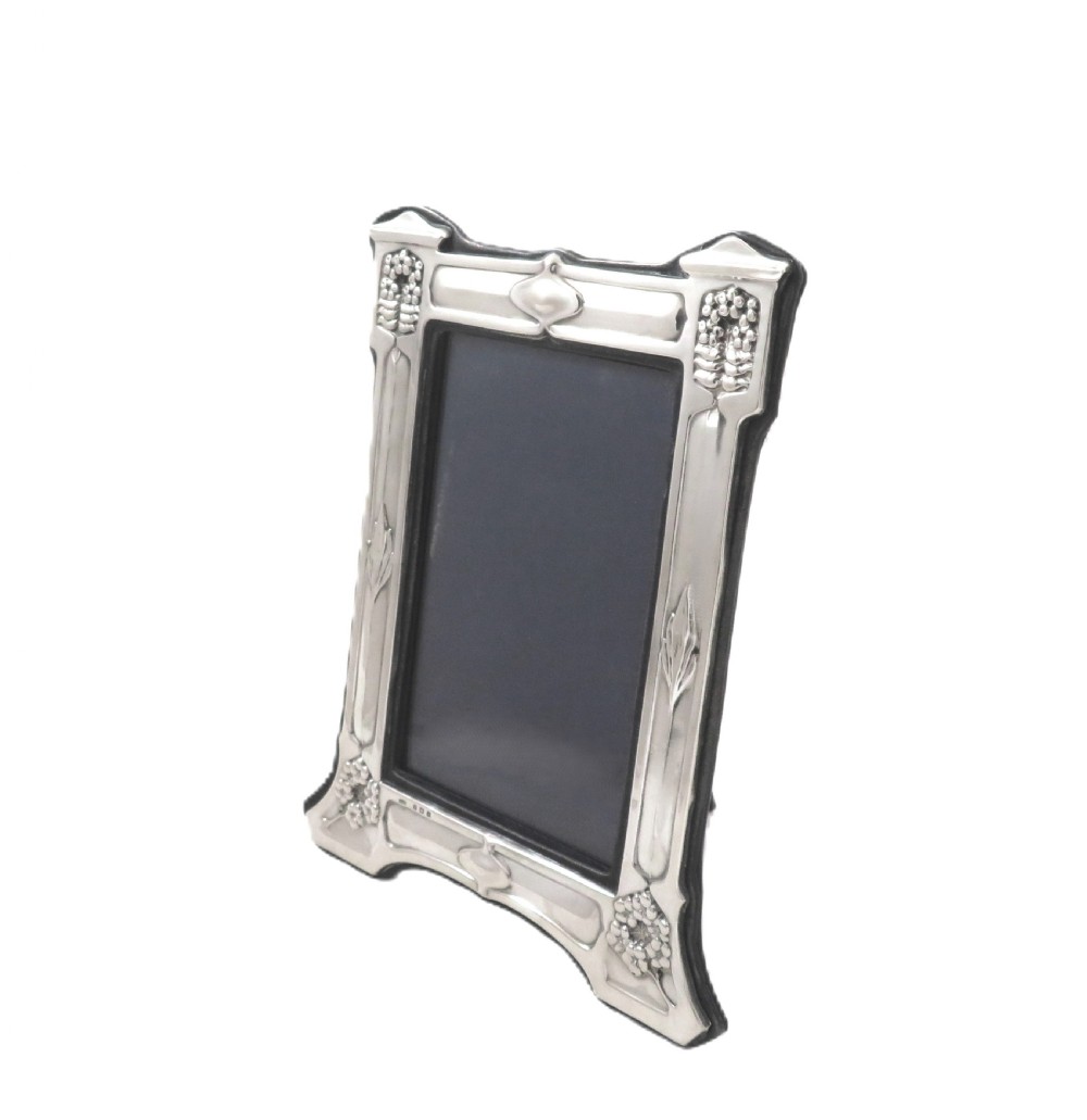 An antique sterling silver Art Nouveau picture frame featuring embossed botanical detailing and a dark easel backing. View VII