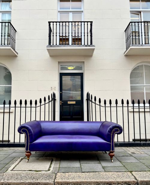 fig 1. A Victorian Chesterfield sofa featuring hand-dyed purple leather upholstery, brass studding, and turned timber legs with castors.