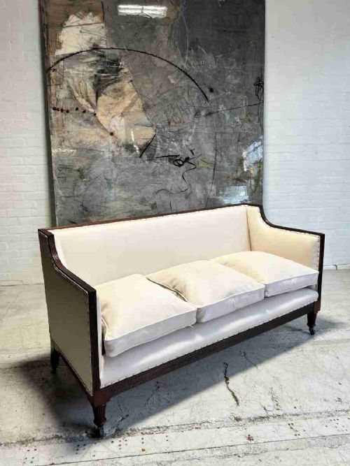 fig 1. A restored 19th-century three-seater sofa with off-white leather upholstery, reeded mahogany frame, and turned legs on brass castors.