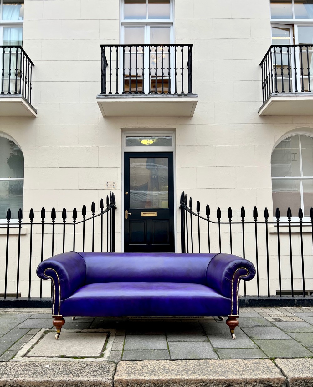 A Victorian Chesterfield sofa featuring hand-dyed purple leather upholstery, brass studding, and turned timber legs with castors. View II