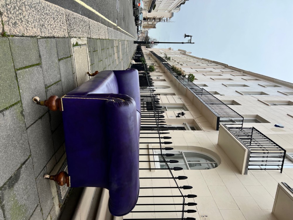 A Victorian Chesterfield sofa featuring hand-dyed purple leather upholstery, brass studding, and turned timber legs with castors. View III