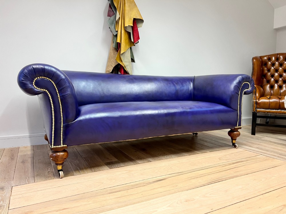 A Victorian Chesterfield sofa featuring hand-dyed purple leather upholstery, brass studding, and turned timber legs with castors. View VIII