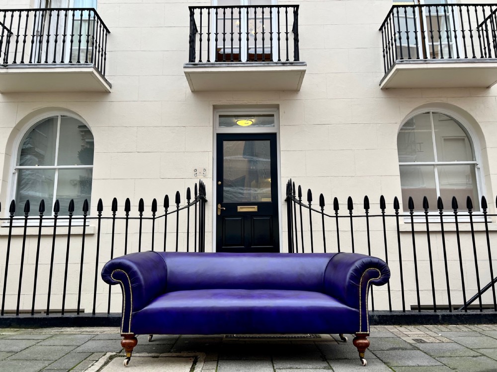 A Victorian Chesterfield sofa featuring hand-dyed purple leather upholstery, brass studding, and turned timber legs with castors. View XI