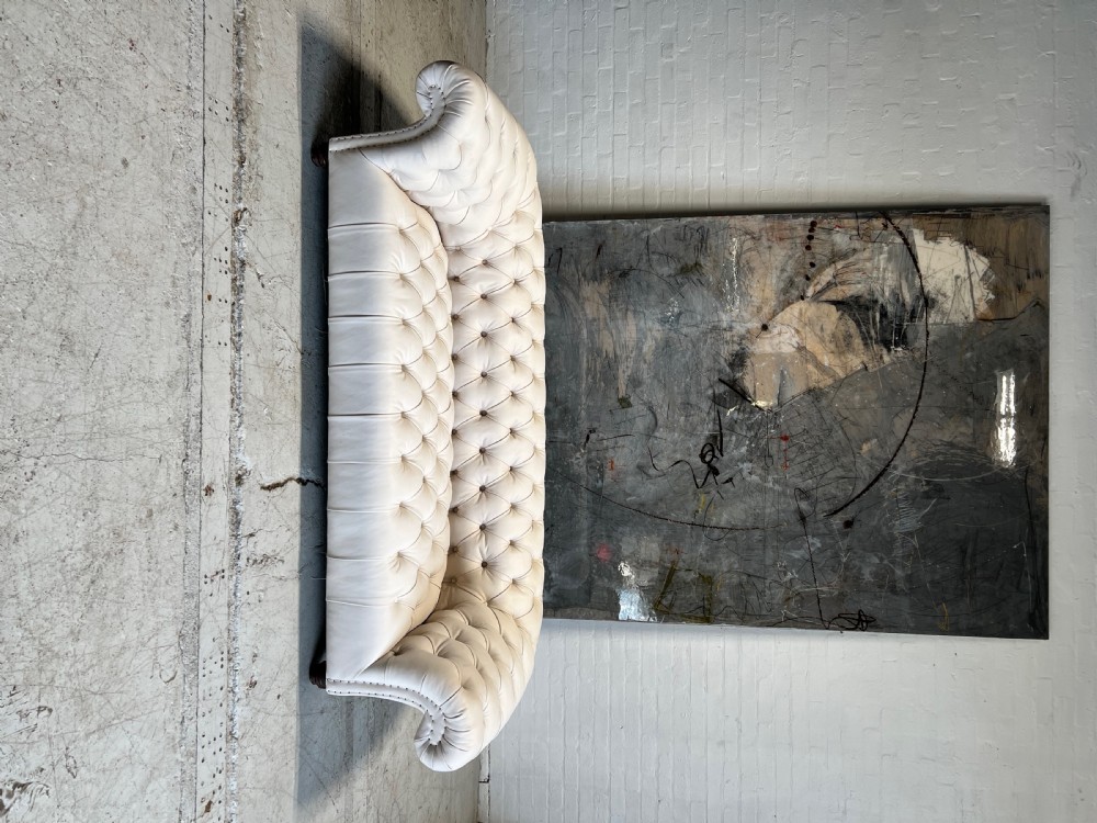 A restored 19th-century Victorian Chesterfield sofa upholstered in natural off-white undyed leather with deep buttoning and turned wood legs. View VII