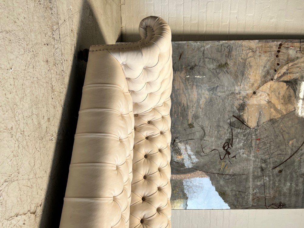 A restored 19th-century Victorian Chesterfield sofa upholstered in natural off-white undyed leather with deep buttoning and turned wood legs. View VIII
