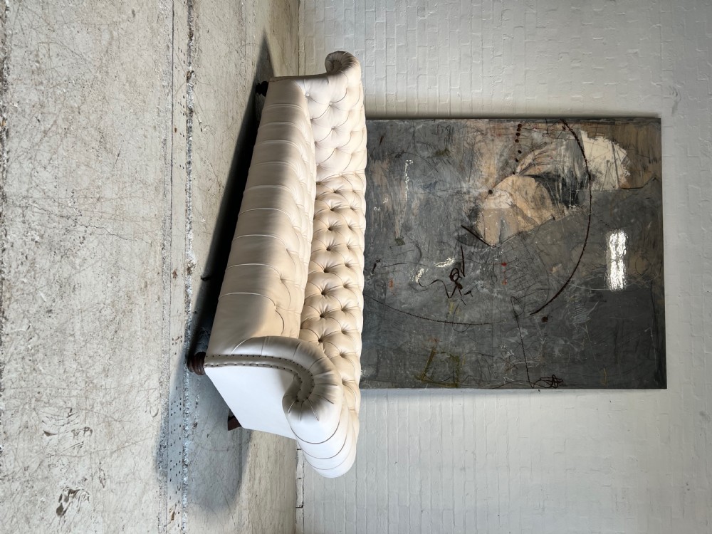 A restored 19th-century Victorian Chesterfield sofa upholstered in natural off-white undyed leather with deep buttoning and turned wood legs. View IX