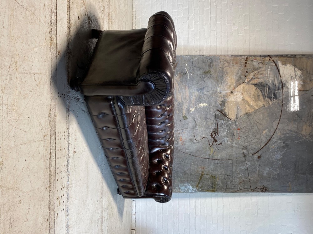 A nineteenth-century Chesterfield sofa upholstered in deep aubergine buttoned leather with rolled arms and turned wooden feet. View II
