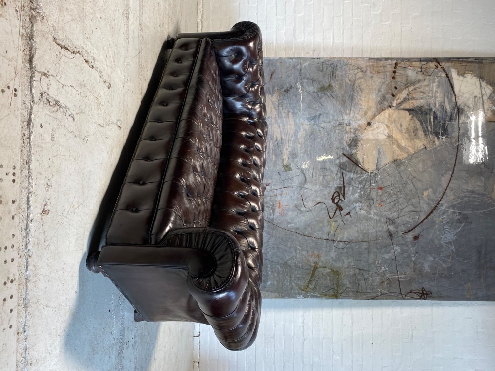 A nineteenth-century Chesterfield sofa upholstered in deep aubergine buttoned leather with rolled arms and turned wooden feet. View V