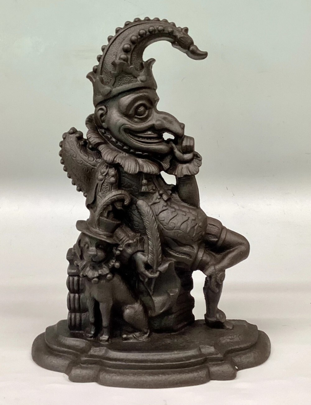 A Victorian cast iron doorstop depicting the character Mr Punch seated next to Toby the dog on a stepped base.