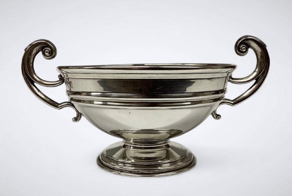 An Edwardian sterling silver twin-handled bowl with high scroll handles and a stepped pedestal base.