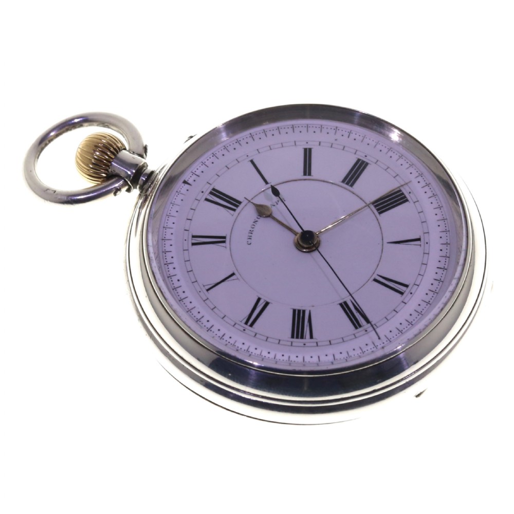 An antique silver open-face chronograph pocket watch featuring a white enamel dial with black Roman numerals and a brass winding crown. View X
