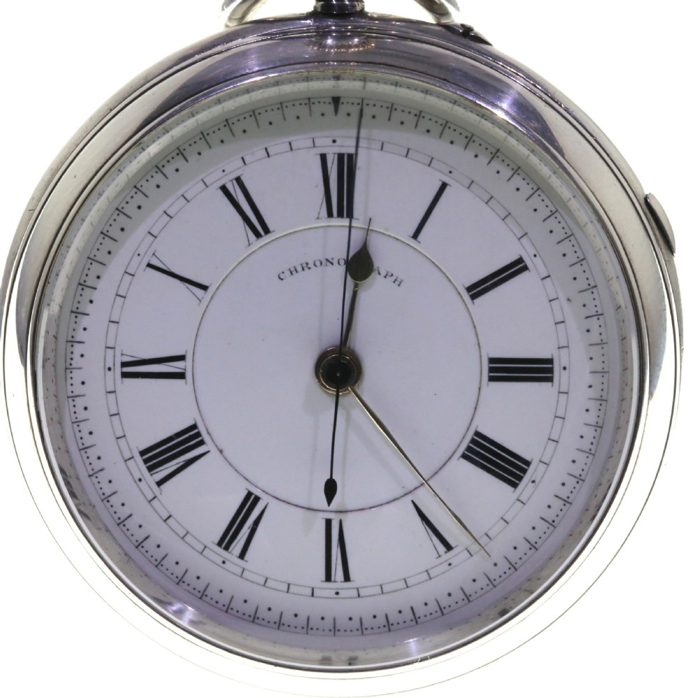 An antique silver open-face chronograph pocket watch featuring a white enamel dial with black Roman numerals and a brass winding crown. View XI