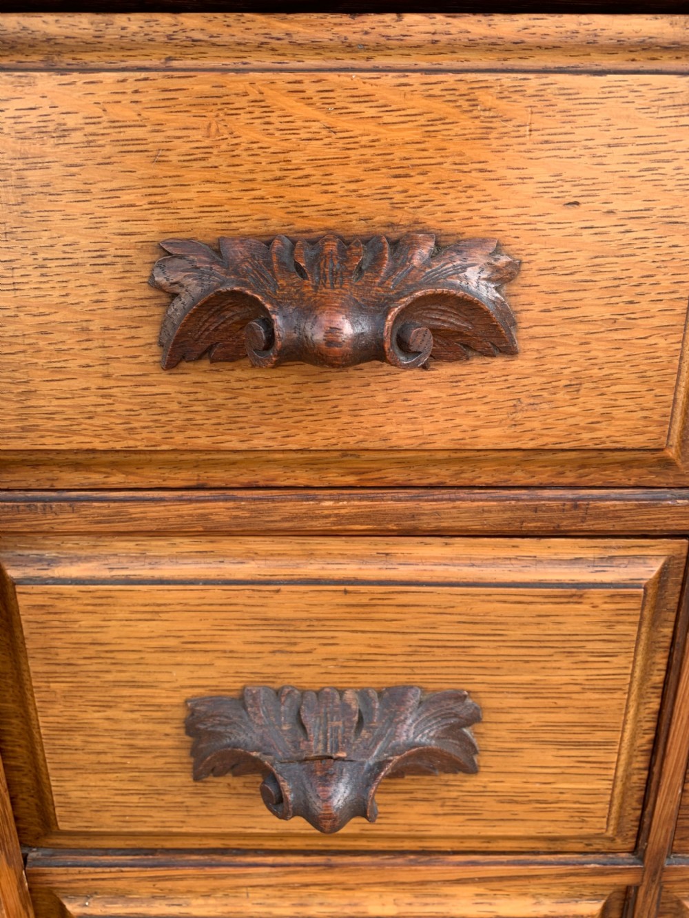 A tall Victorian oak Wellington chest featuring twelve drawers arranged in two columns with carved wooden pulls set on a solid plinth base. View II