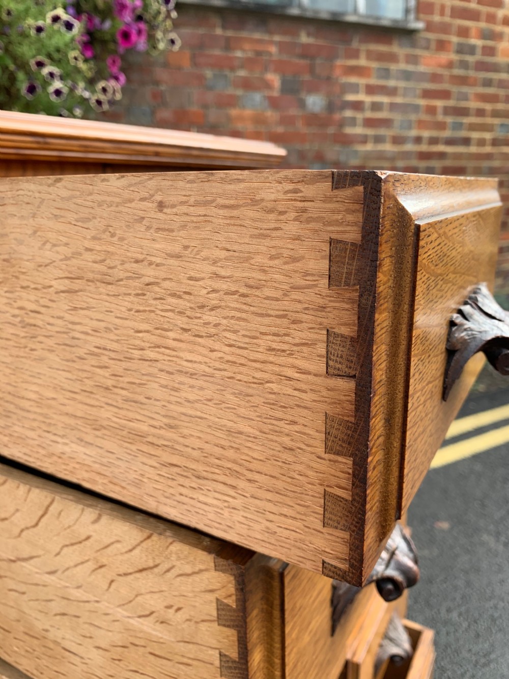 A tall Victorian oak Wellington chest featuring twelve drawers arranged in two columns with carved wooden pulls set on a solid plinth base. View V