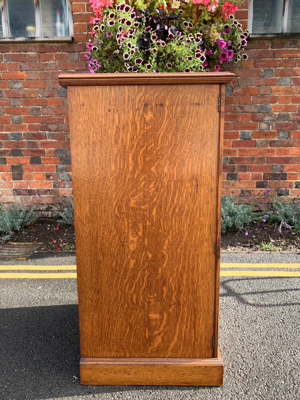 A tall Victorian oak Wellington chest featuring twelve drawers arranged in two columns with carved wooden pulls set on a solid plinth base. View VII