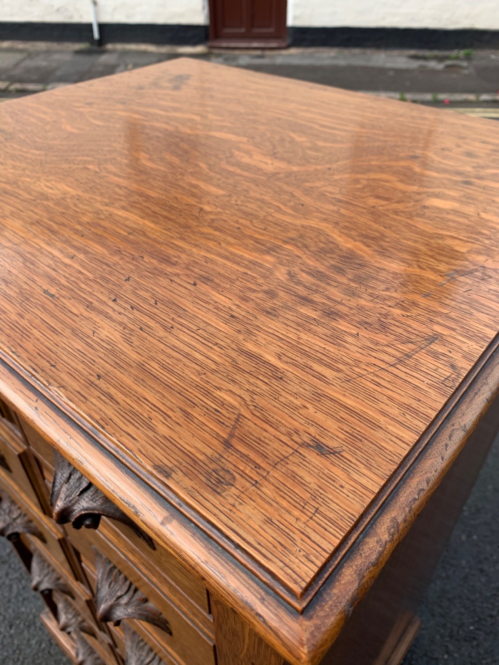 A tall Victorian oak Wellington chest featuring twelve drawers arranged in two columns with carved wooden pulls set on a solid plinth base. View IX