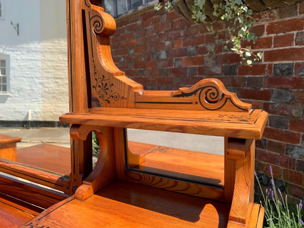 An Aesthetic Movement wooden dressing table featuring a central adjustable mirror, elevated trinket drawers, incised floral carvings, and turned legs on castors. View V