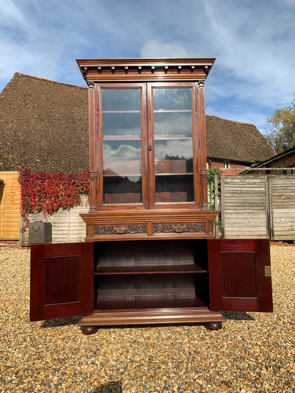 A tall Victorian mahogany bookcase with two upper glazed doors, two carved drawers, and lower carved cupboard doors. View II