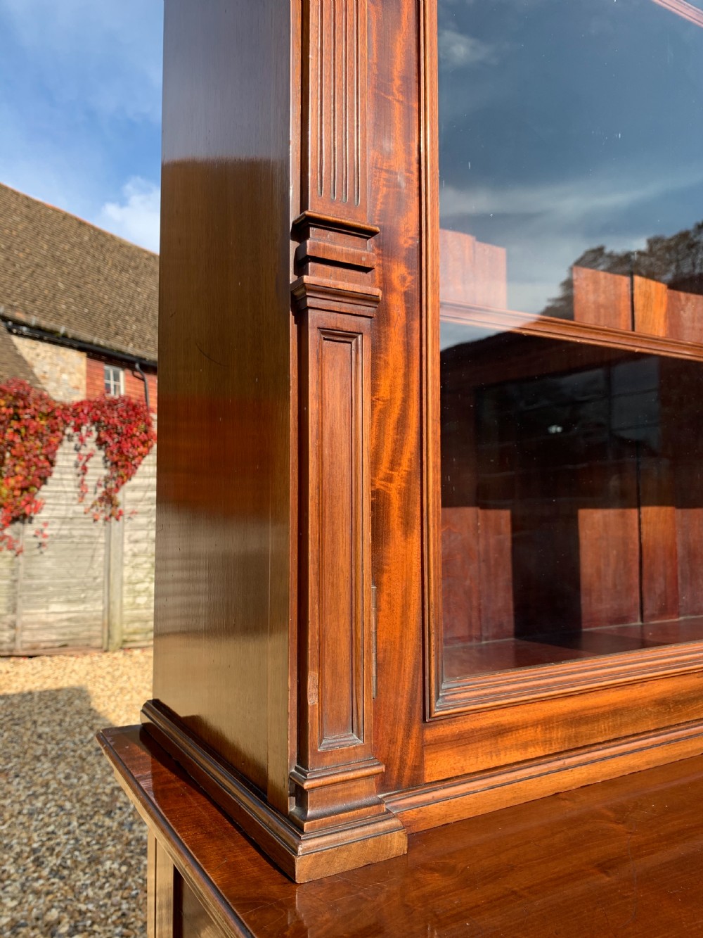 A tall Victorian mahogany bookcase with two upper glazed doors, two carved drawers, and lower carved cupboard doors. View VI