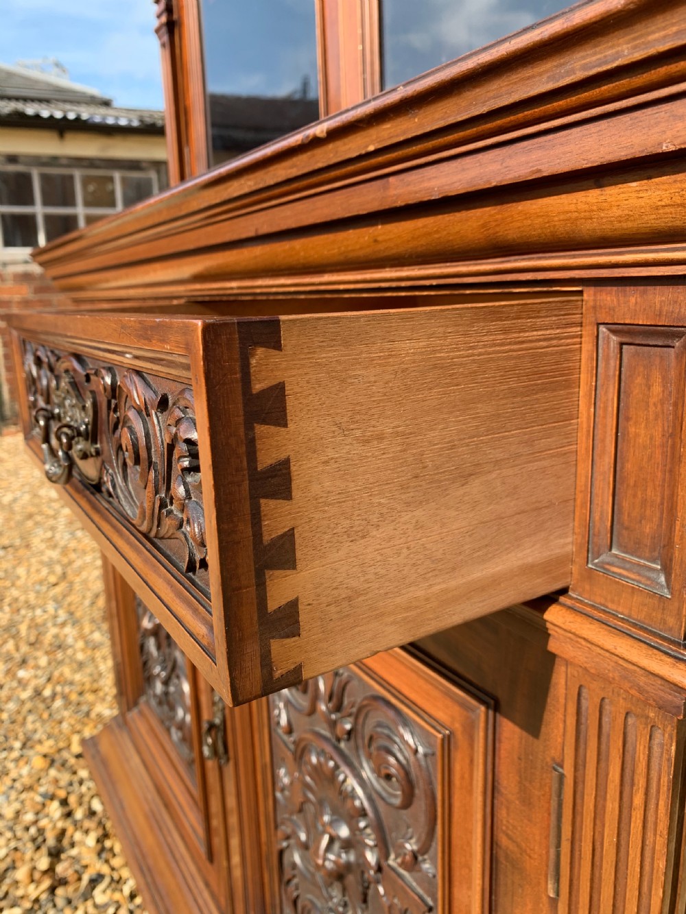 A tall Victorian mahogany bookcase with two upper glazed doors, two carved drawers, and lower carved cupboard doors. View X