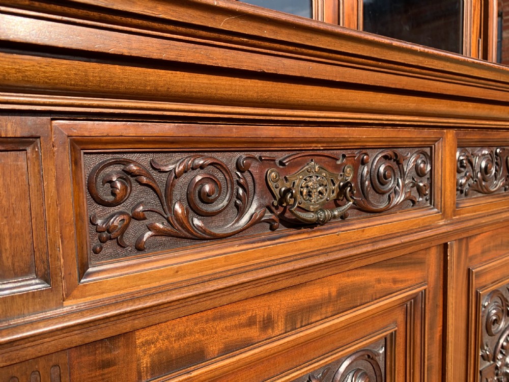 A tall Victorian mahogany bookcase with two upper glazed doors, two carved drawers, and lower carved cupboard doors. View XII