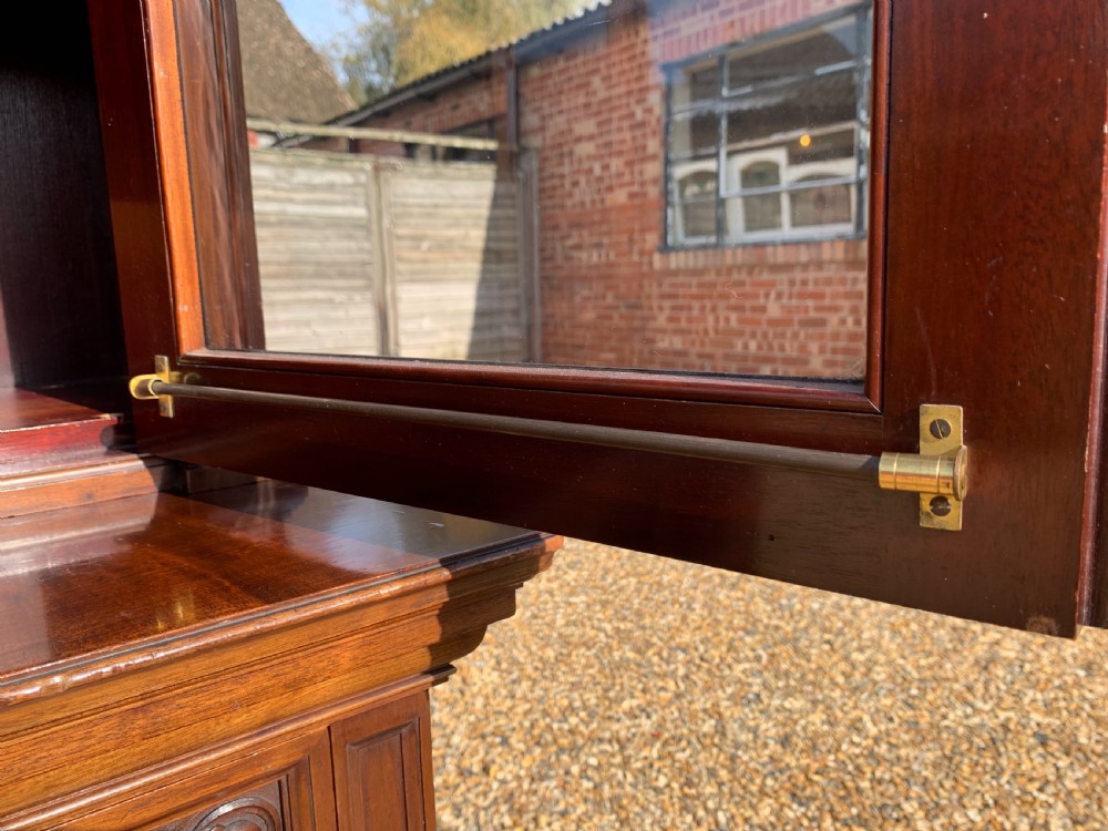 A tall Victorian mahogany bookcase with two upper glazed doors, two carved drawers, and lower carved cupboard doors. View XIV