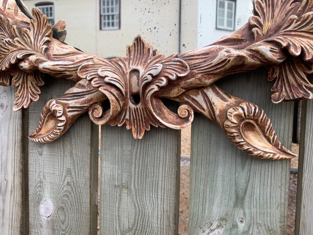 A pair of oval wall mirrors featuring ornate carved wooden frames with oak leaf motifs and ribbon crests in a painted finish. View V