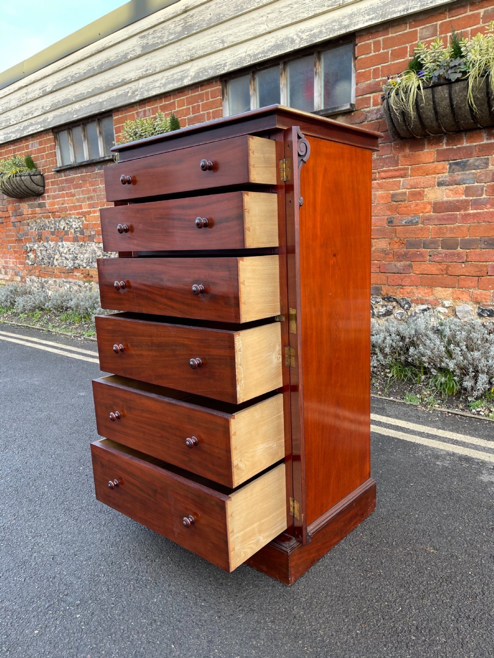 A tall Victorian mahogany Wellington chest featuring seven graduated drawers with turned wooden knobs, carved side corbels, and a side locking pilaster. View VIII