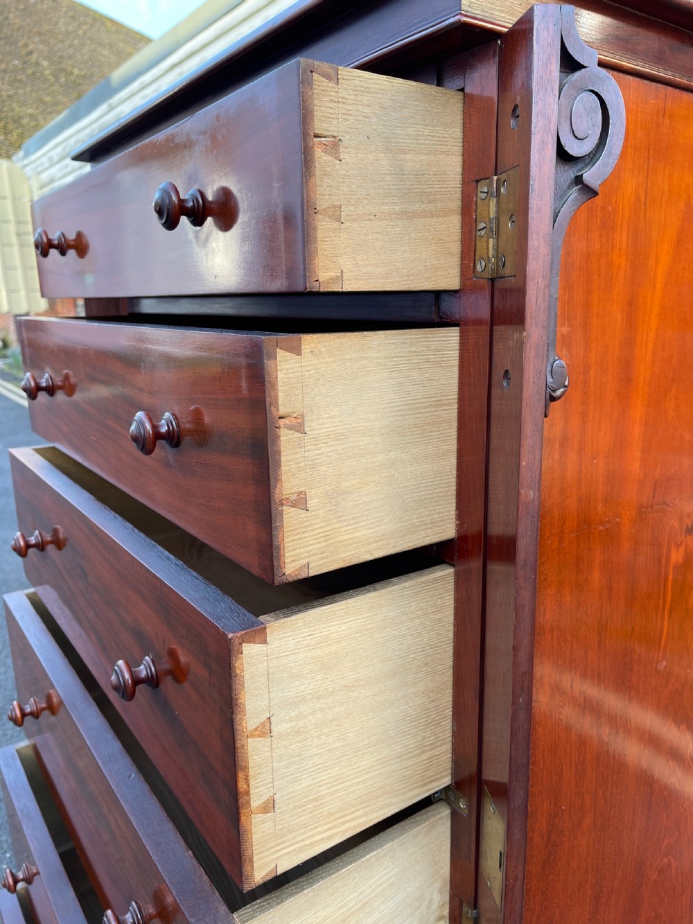 A tall Victorian mahogany Wellington chest featuring seven graduated drawers with turned wooden knobs, carved side corbels, and a side locking pilaster. View IX