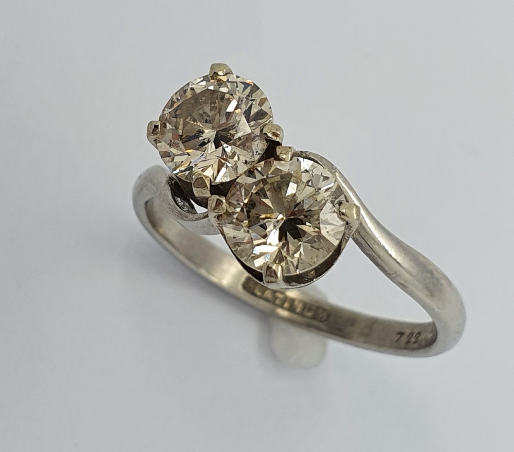 A platinum ring featuring two claw-set round brilliant diamonds in a curved crossover twist band. View III
