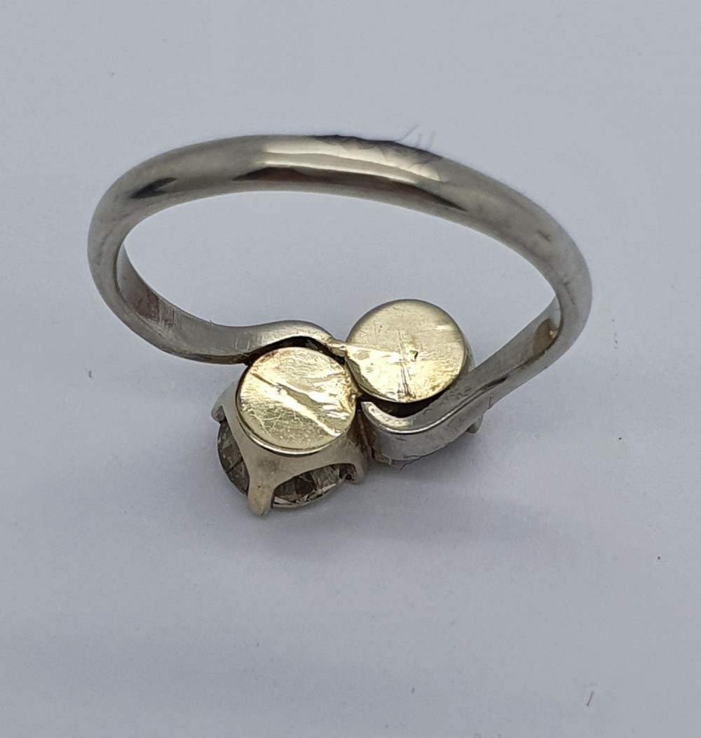 A platinum ring featuring two claw-set round brilliant diamonds in a curved crossover twist band. View V