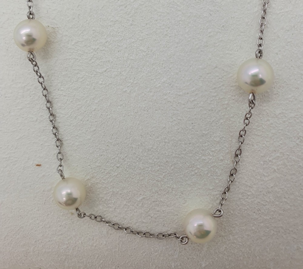 An 18ct white gold chain necklace set with evenly spaced round cream Akoya pearls along its length. View II