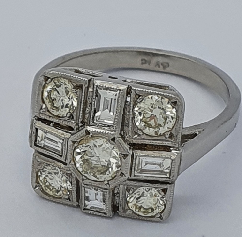 An Art Deco platinum cocktail ring featuring a geometric rectangular plaque setting filled with round and rectangular diamonds and detailed millegrain edging. View II