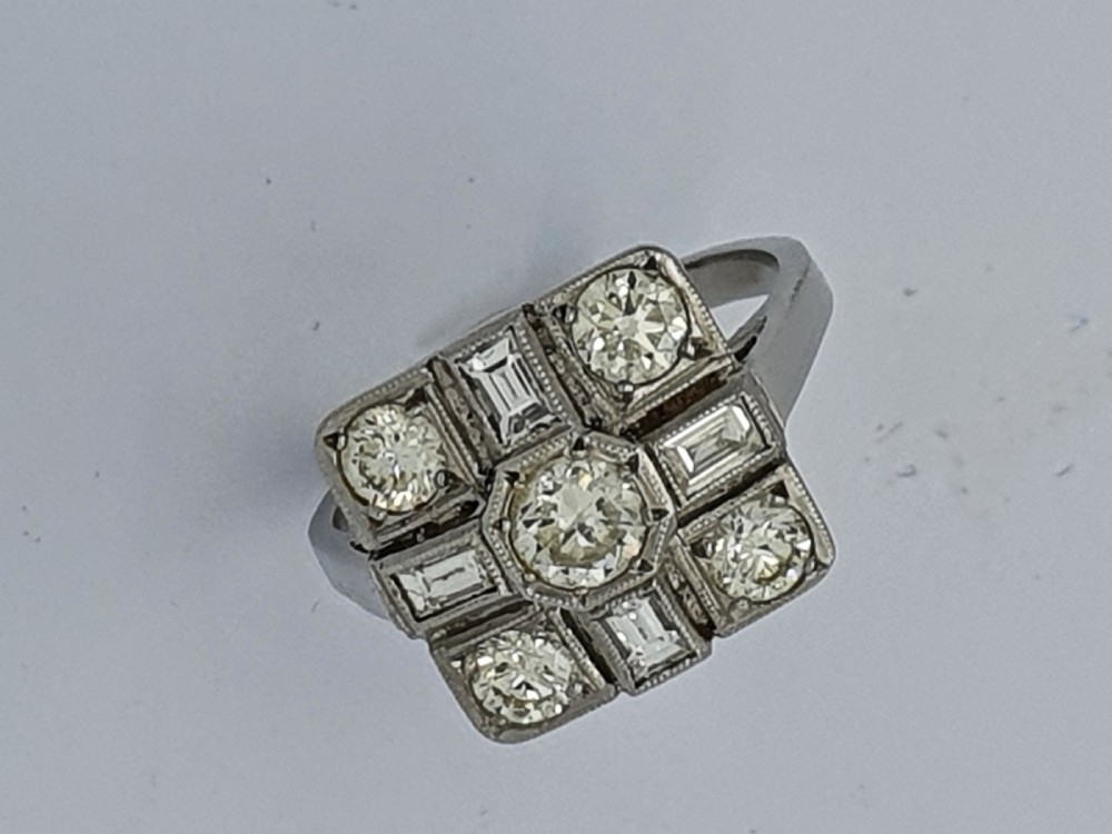 An Art Deco platinum cocktail ring featuring a geometric rectangular plaque setting filled with round and rectangular diamonds and detailed millegrain edging. View VII