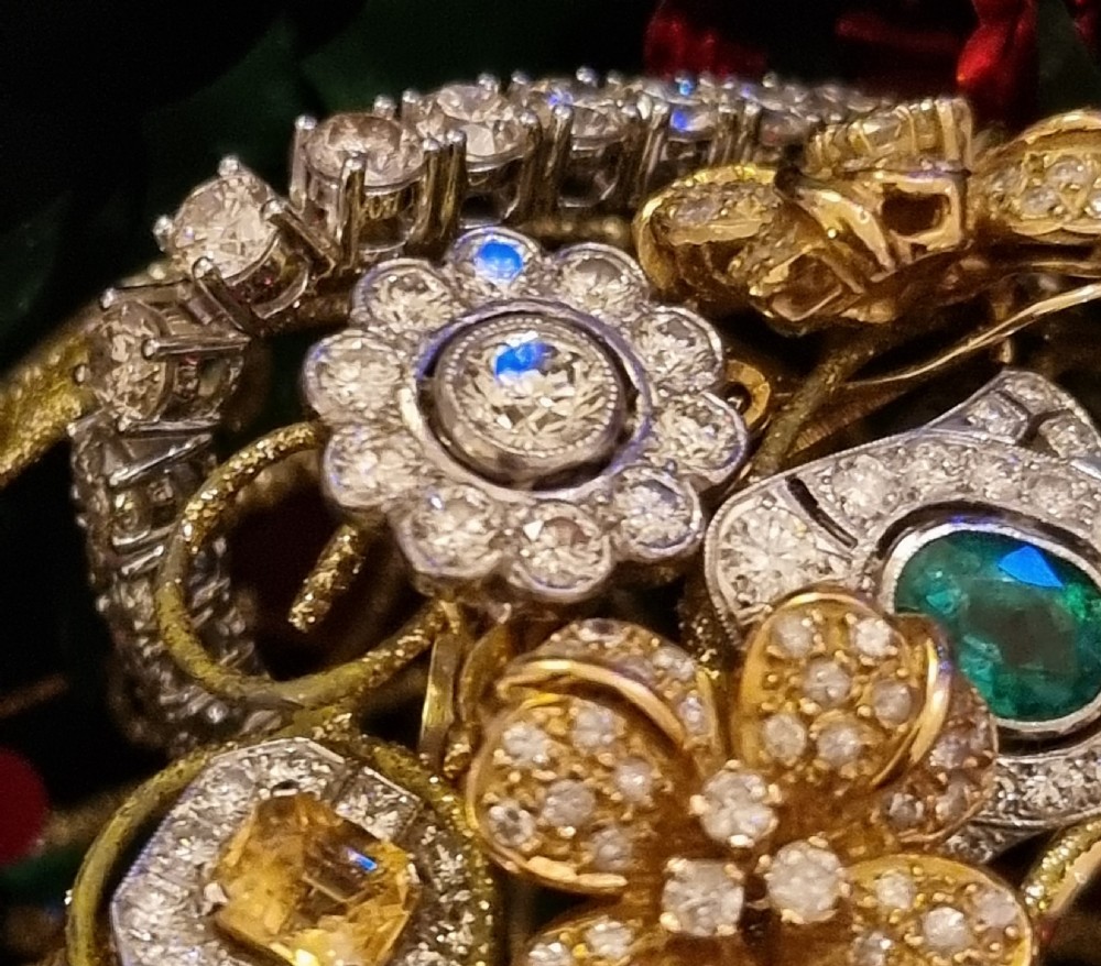 An antique diamond cluster ring featuring a central round diamond encircled by ten smaller diamonds set in a white metal head with a yellow gold band. View IV