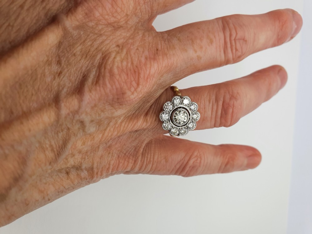 An antique diamond cluster ring featuring a central round diamond encircled by ten smaller diamonds set in a white metal head with a yellow gold band. View V