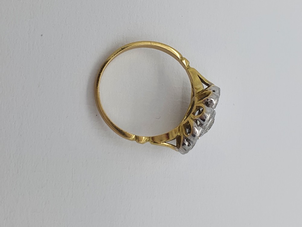 An antique diamond cluster ring featuring a central round diamond encircled by ten smaller diamonds set in a white metal head with a yellow gold band. View IX