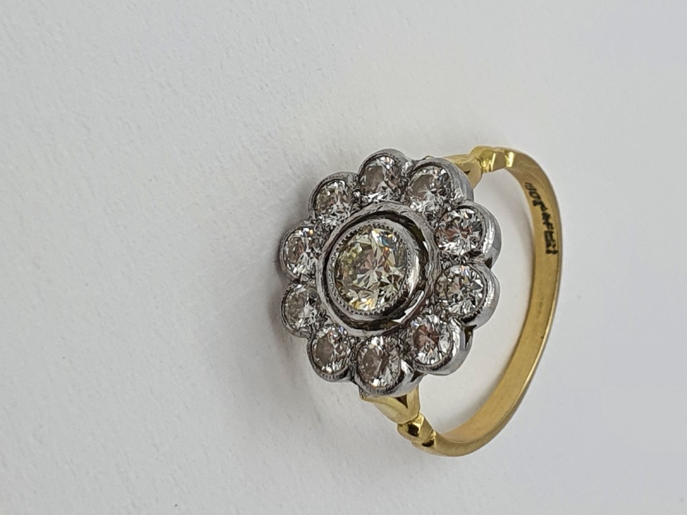 An antique diamond cluster ring featuring a central round diamond encircled by ten smaller diamonds set in a white metal head with a yellow gold band. View XI