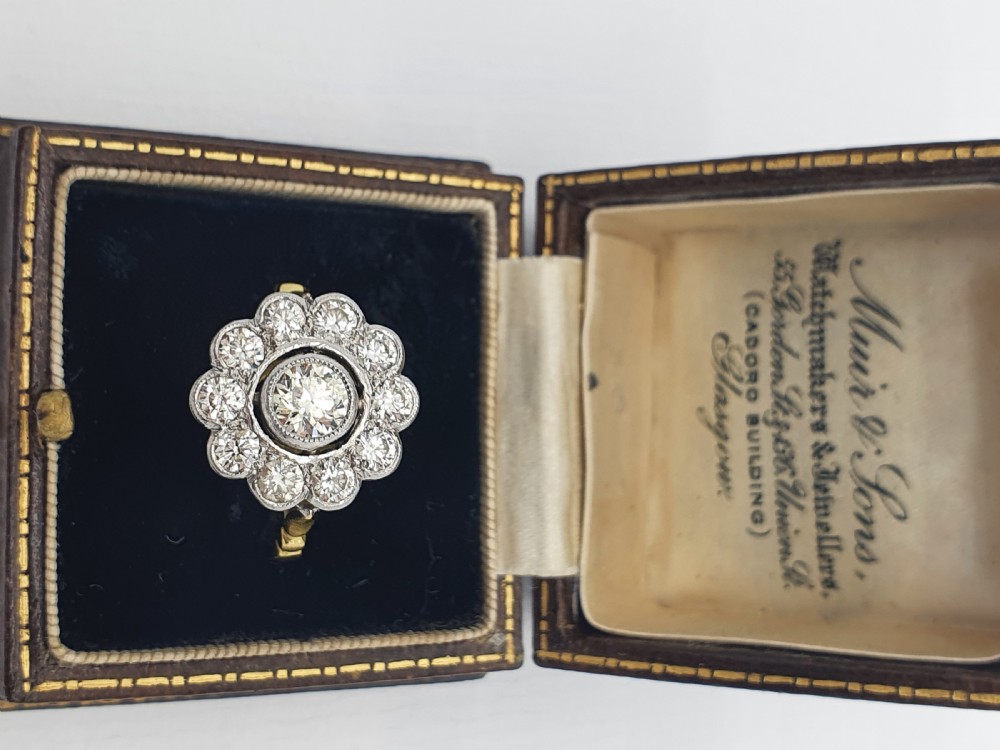 An antique diamond cluster ring featuring a central round diamond encircled by ten smaller diamonds set in a white metal head with a yellow gold band. View XIII
