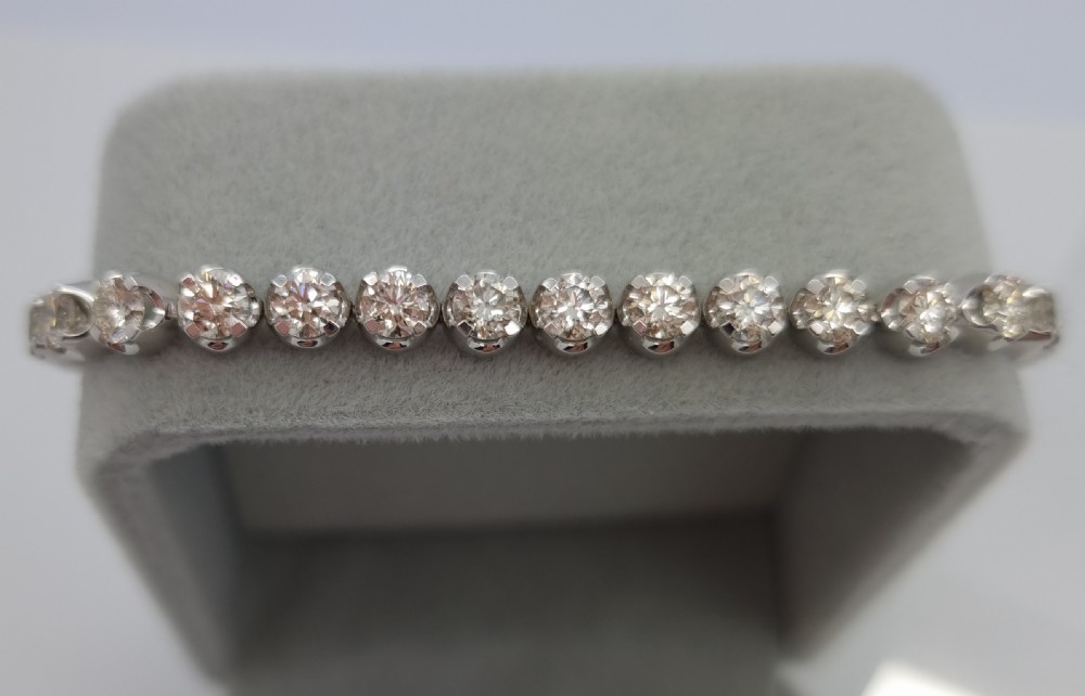 A flexible collet set diamond tennis bracelet crafted in white metal with a continuous row of round brilliant cut diamonds. View II