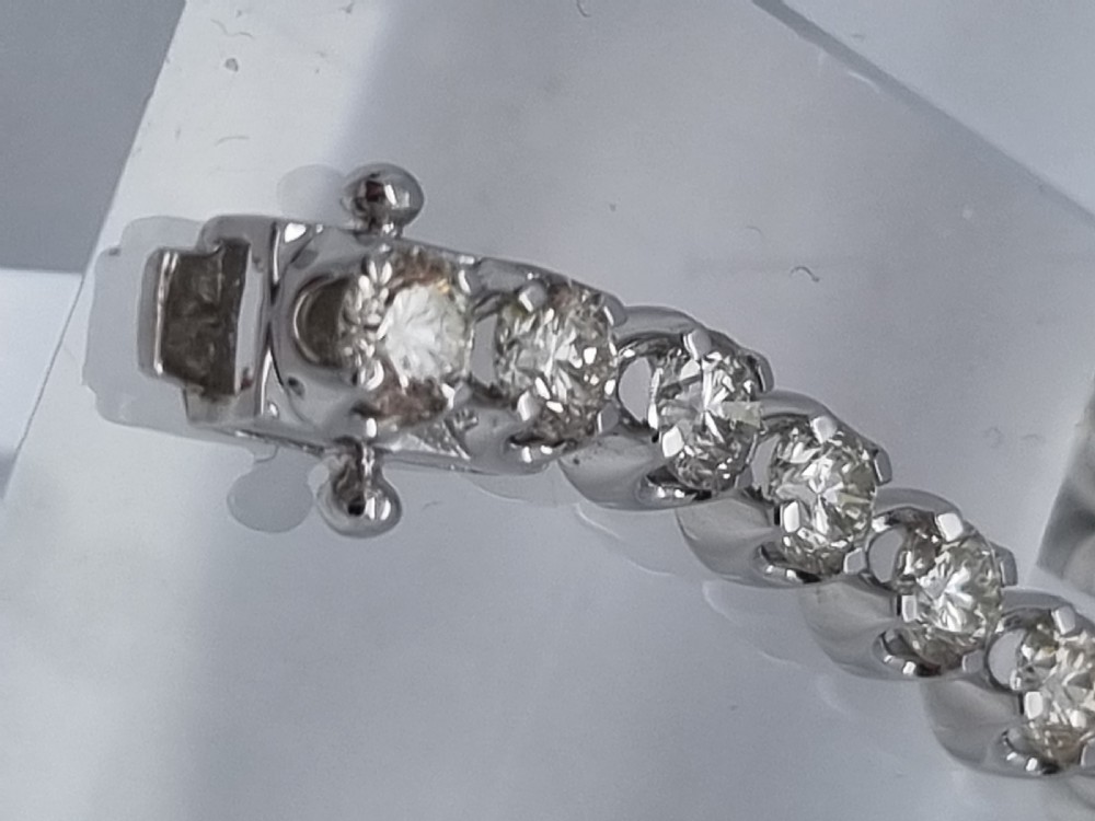 A flexible collet set diamond tennis bracelet crafted in white metal with a continuous row of round brilliant cut diamonds. View X
