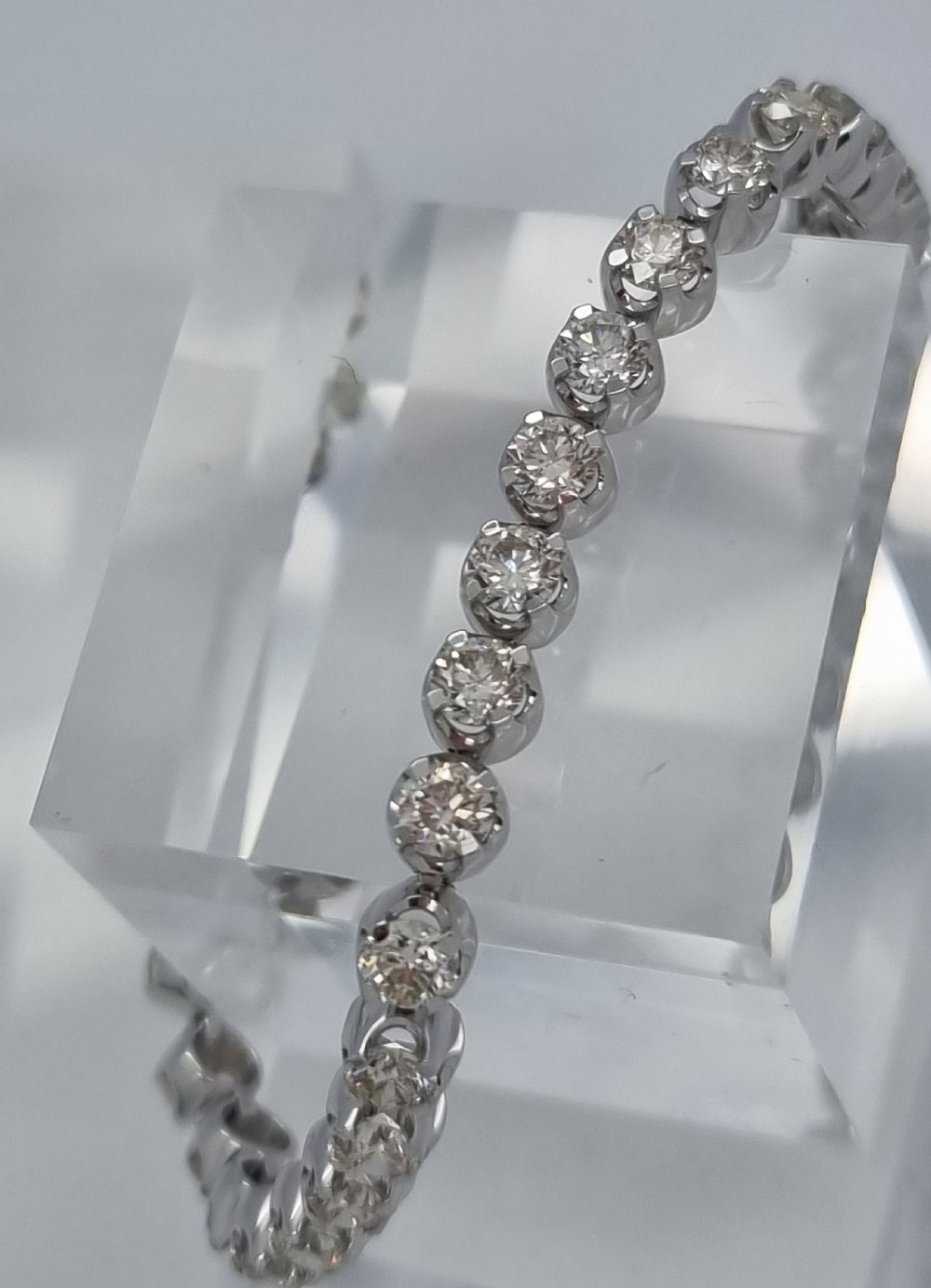 A flexible collet set diamond tennis bracelet crafted in white metal with a continuous row of round brilliant cut diamonds. View XVI