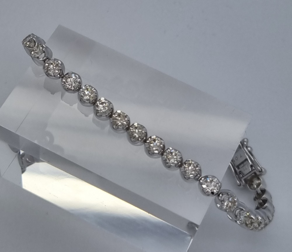 A flexible collet set diamond tennis bracelet crafted in white metal with a continuous row of round brilliant cut diamonds. View XVII