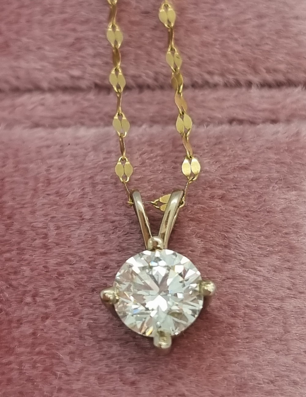 A round brilliant cut diamond set in a four-claw yellow gold pendant mount on a fine chain. View VIII