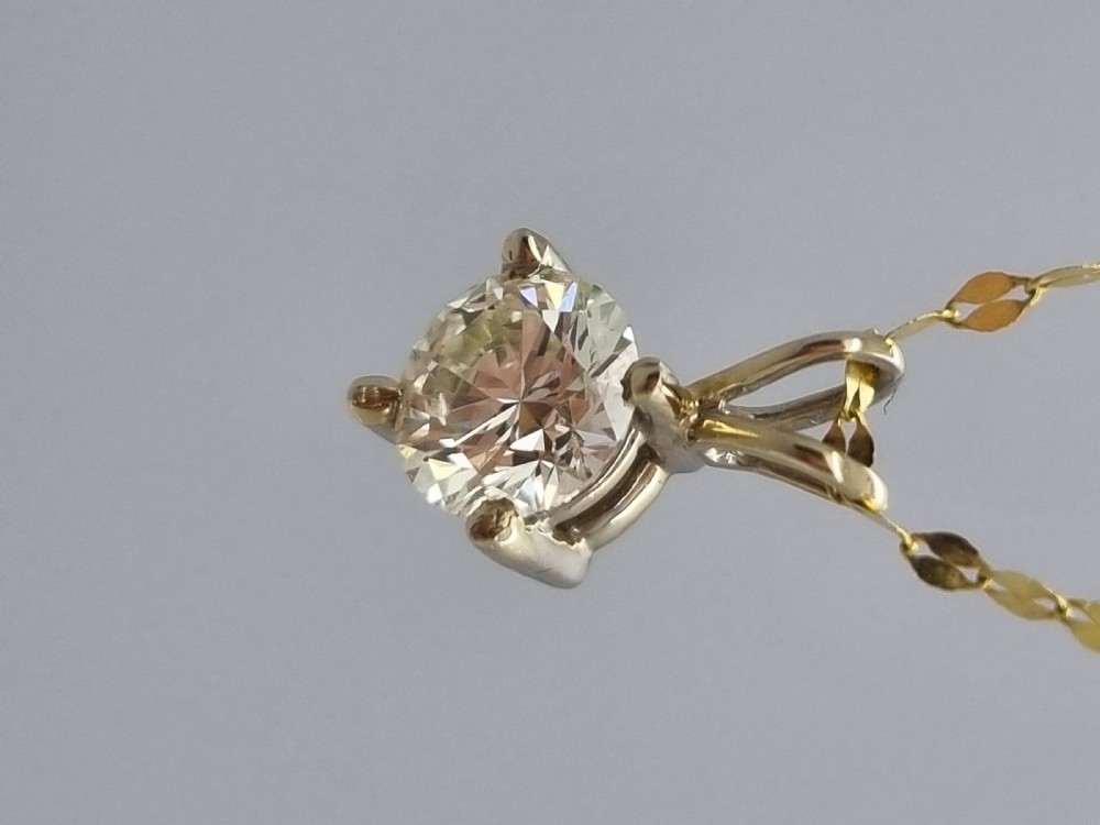 A round brilliant cut diamond set in a four-claw yellow gold pendant mount on a fine chain. View XIII