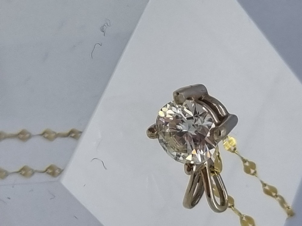 A round brilliant cut diamond set in a four-claw yellow gold pendant mount on a fine chain. View XV