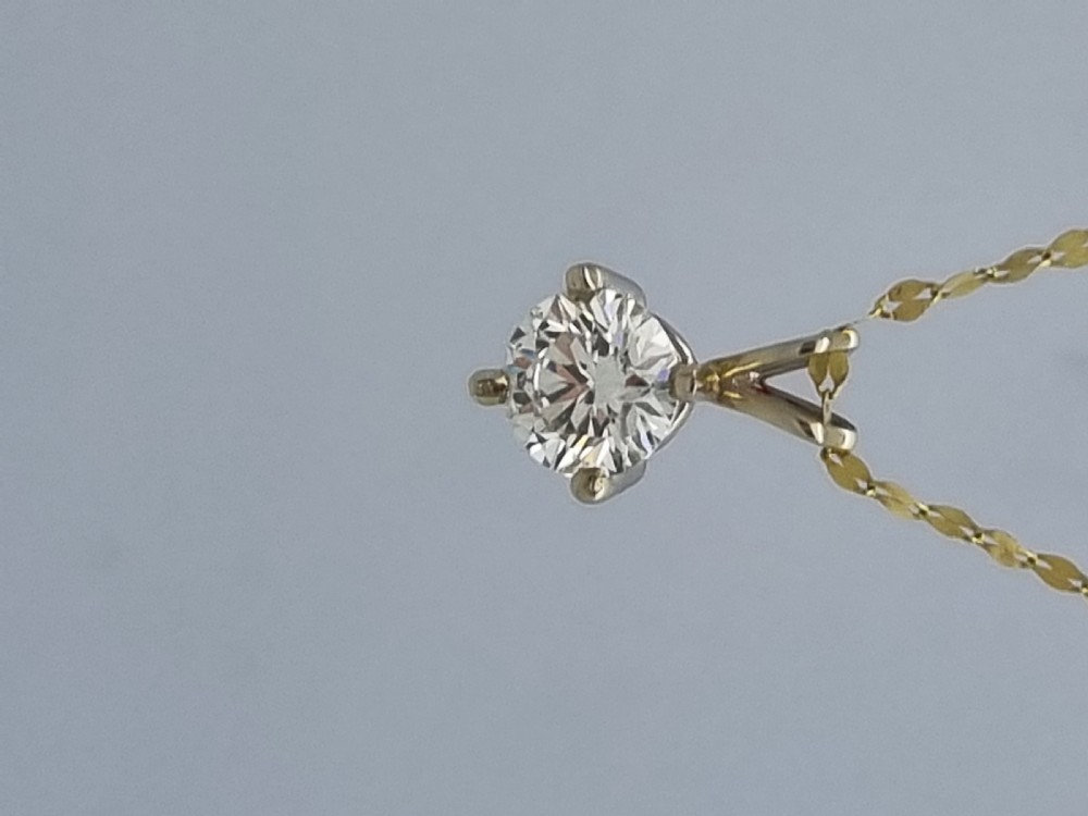 A round brilliant cut diamond set in a four-claw yellow gold pendant mount on a fine chain. View XVI