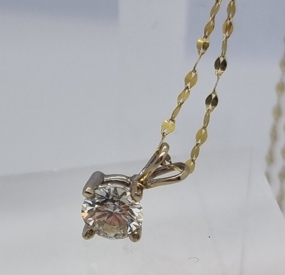 A round brilliant cut diamond set in a four-claw yellow gold pendant mount on a fine chain. View XVII